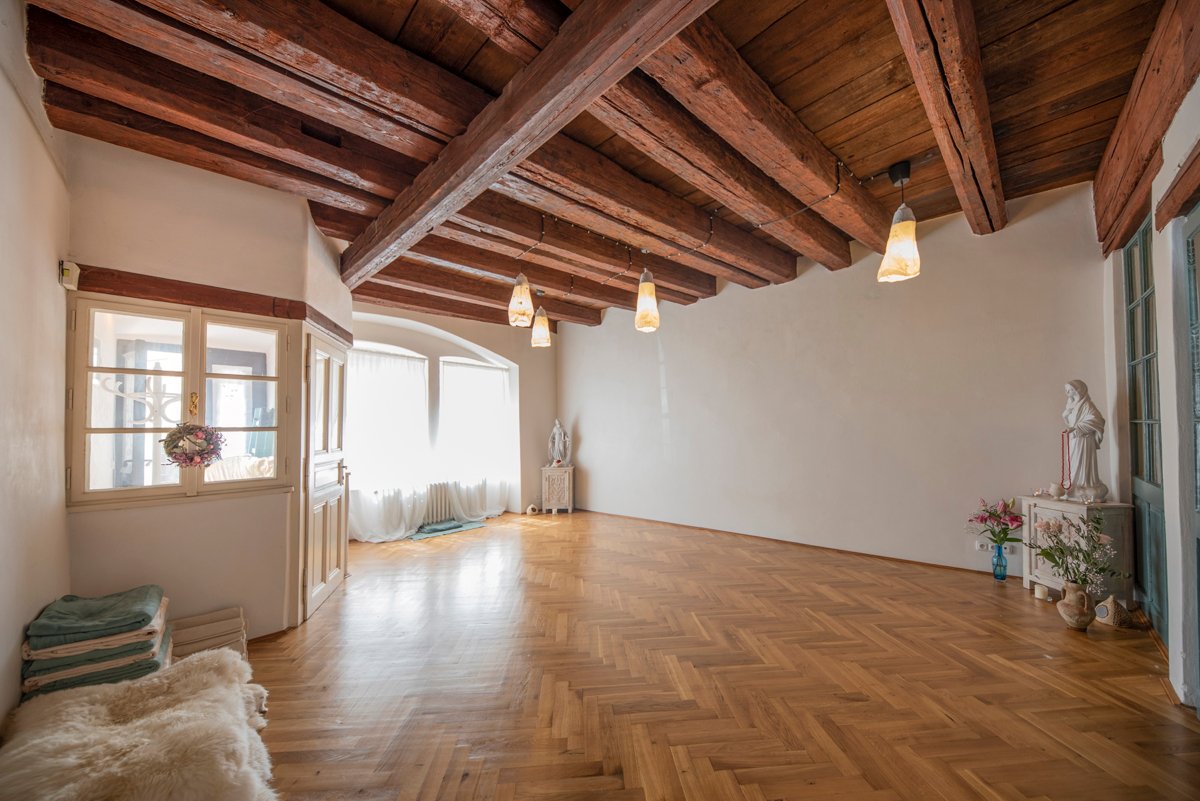 Sál Dračího Chrámu za denního světla, s dřevěnou podlahou a trámovým stropem
